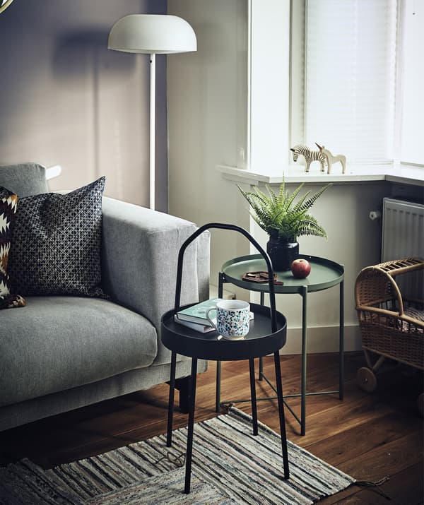 Deux petites tables d’appoint rondes à côté d’un canapé, dans un séjour.