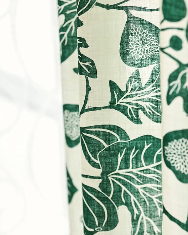 Deux rideaux en tissu pendus côte à côte, l’un en coton blanc translucide, l’autre à motif de feuilles vertes stylisées.