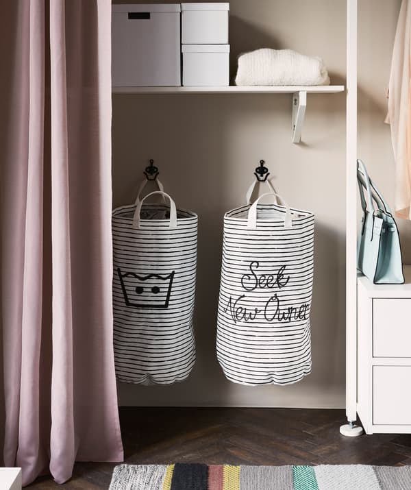 Deux sacs à lessive rayés accrochés dans une penderie
