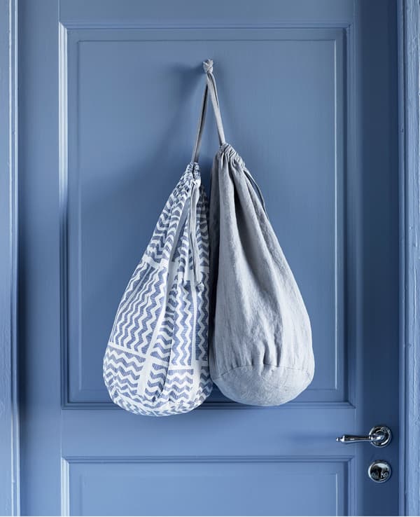 Deux sacs à linge dans différents tissus, accrochés au dos d’une porte.