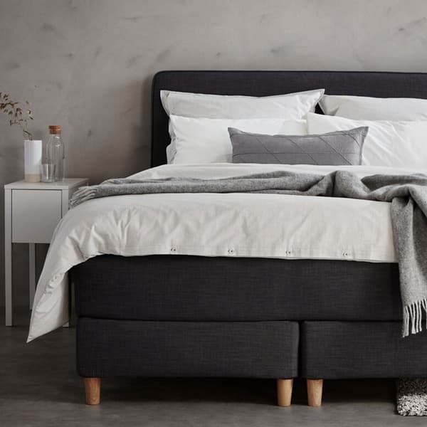 Deux sommiers tapissiers noirs collés avec un matelas et une parure de lit blanche.