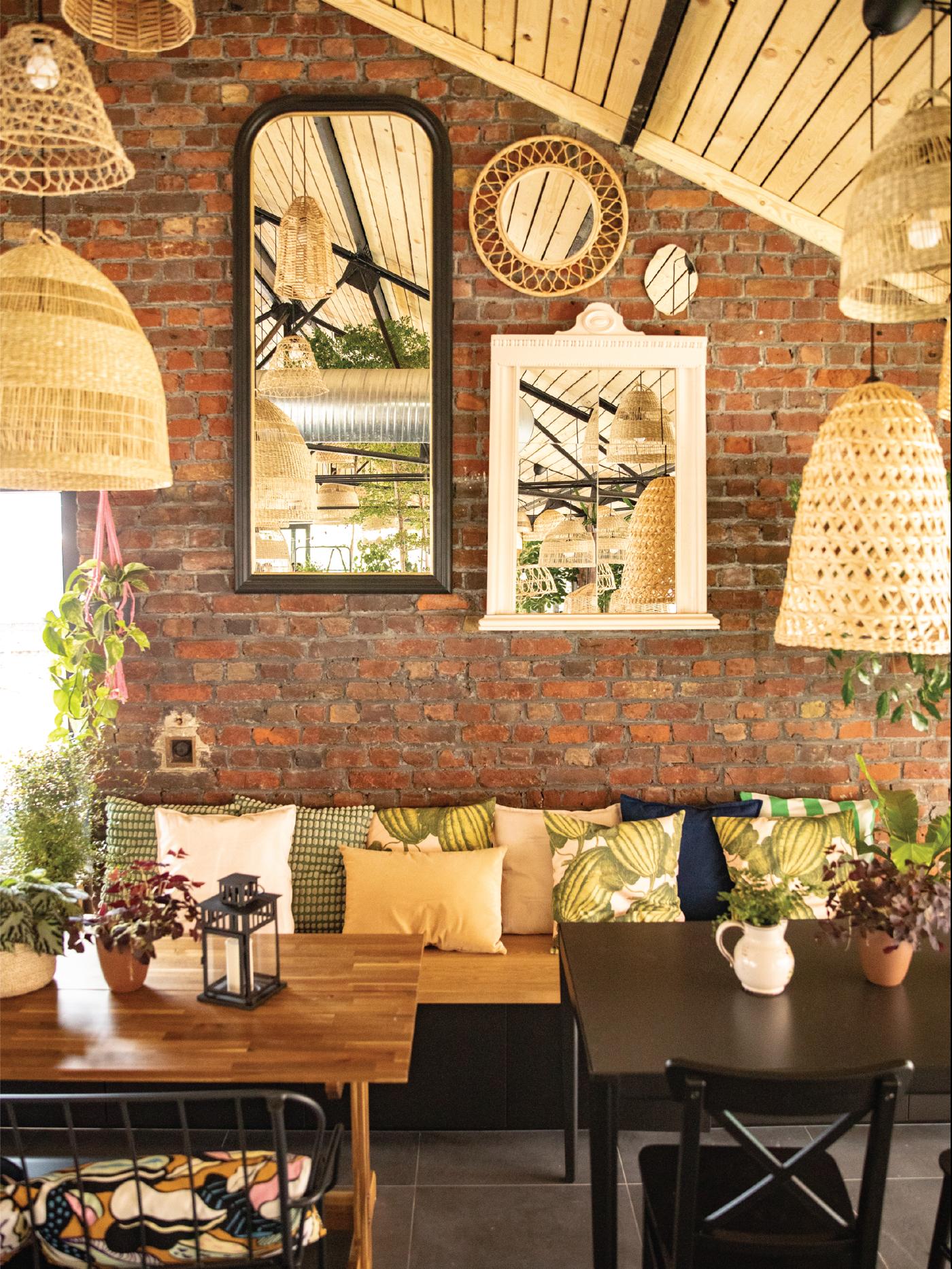 Deux tables de restaurants avec un banc horné de coussins décoratifs et le mur décoré de plusieurs miroirs.