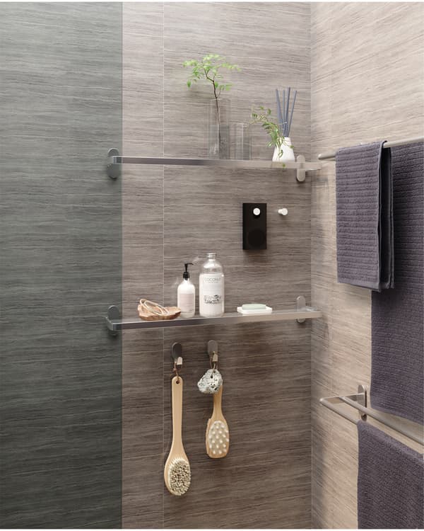 Deux tablettes en verre fixées au mur. Entre elles, deux patères à boutons blanc, dont l’un porte un petit haut-parleur Bluetooth®.