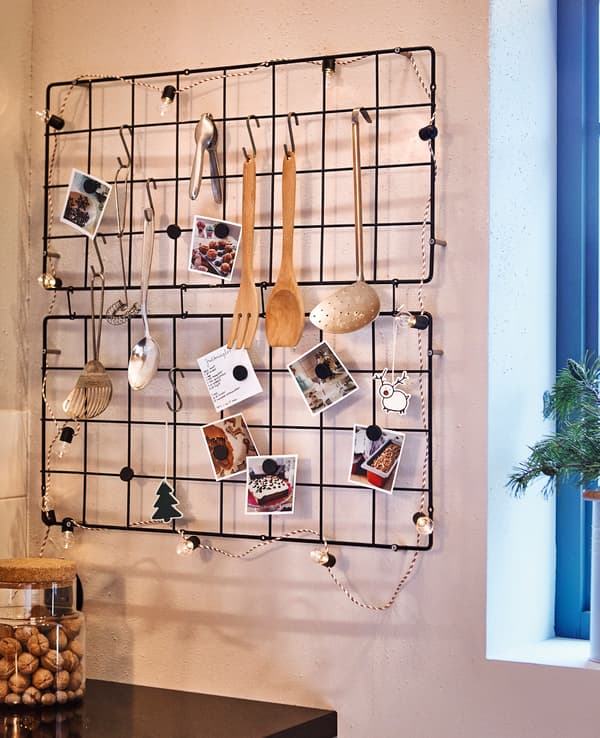 Deux treillis métalliques accrochés au mur de la cuisine, avec ustensiles, recettes et décorations.