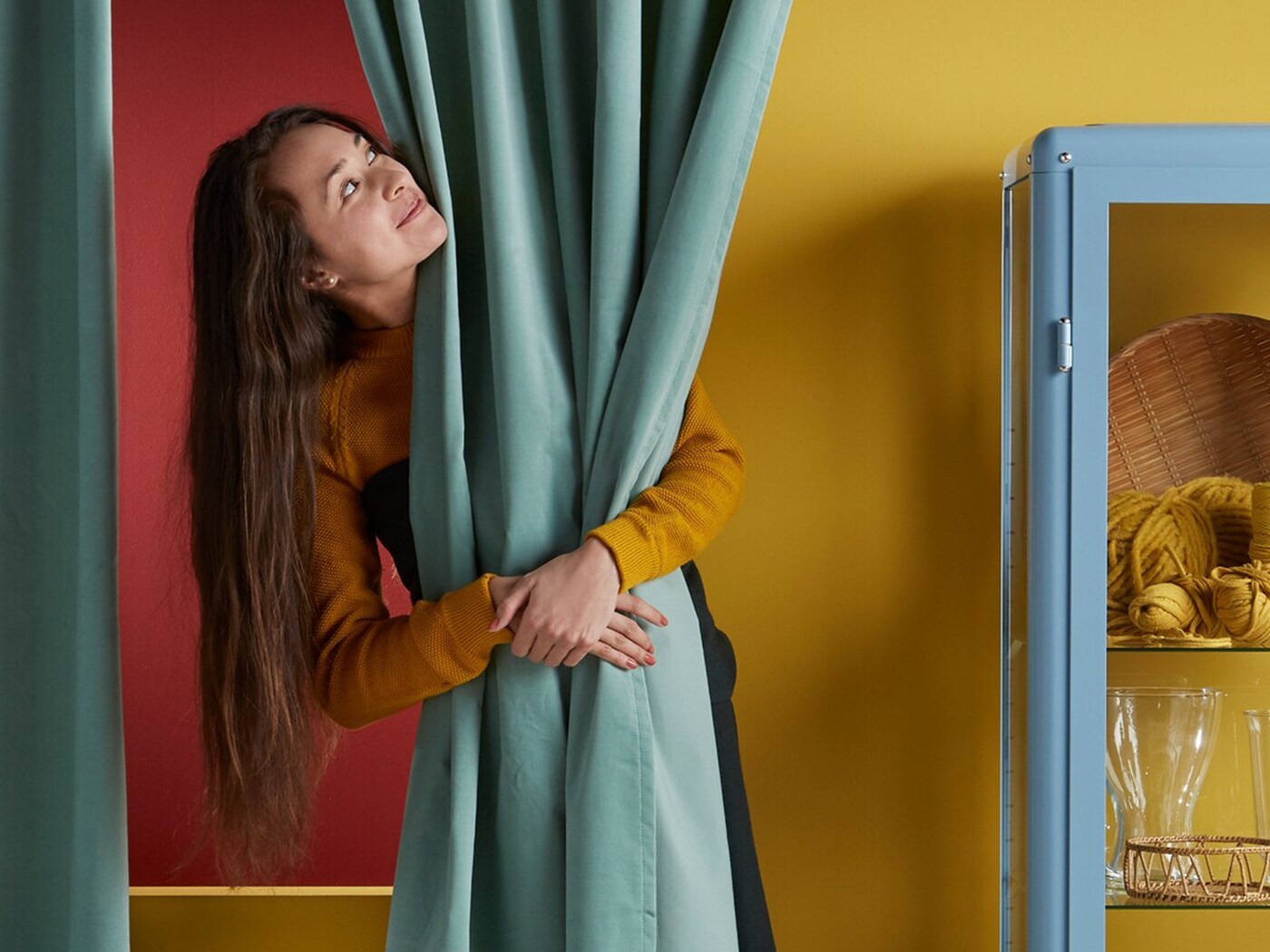 Devojka grli zavesu u izložbenom prostoru robne kuće IKEA