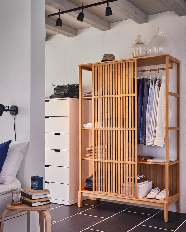 Di belakang dinding bilik tidur terdapat almari pakaian terbuka NORDKISA yang dibuat daripada buluh, pintu gelangsar berada di tengah-tengah dan mendedahkan pakaian pada rel.