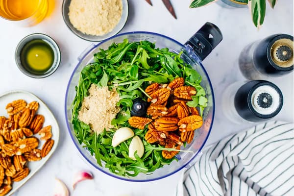 Die Zutaten für frisches Pesto befinden sich in einem Mixer.