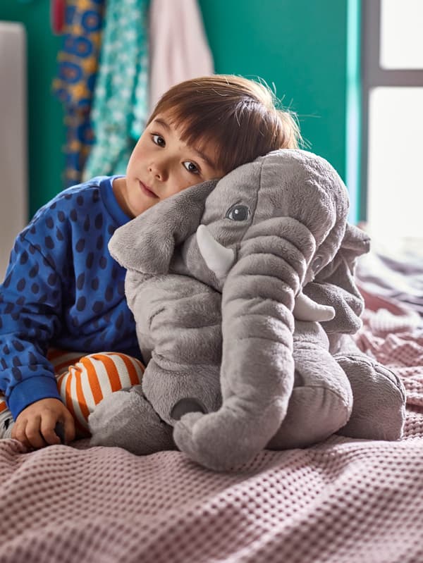 Dieťa v modrom tričku objíma plyšového slona JÄTTESTOR.