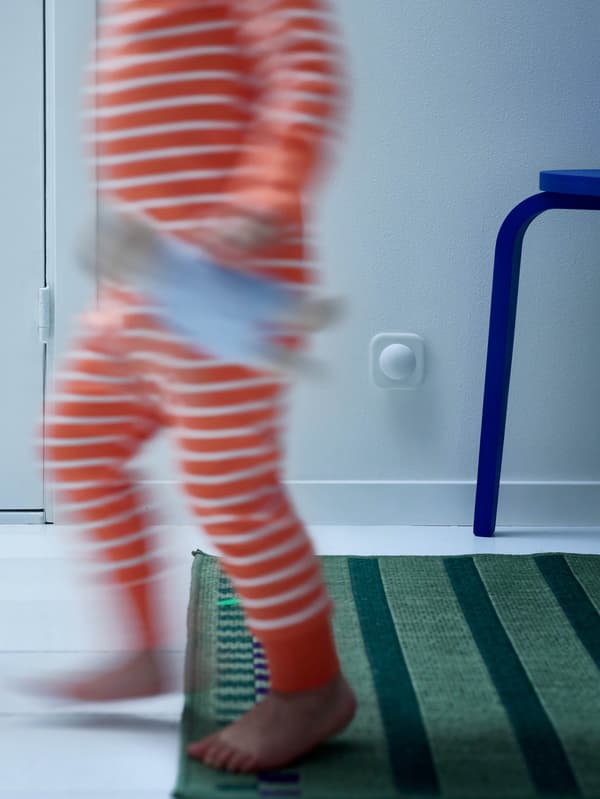 Dieťa v pruhovanom pyžame s medvedíkom FABLER BJÖRN v ruke prechádza okolo pohybového senzora VALLHORN.