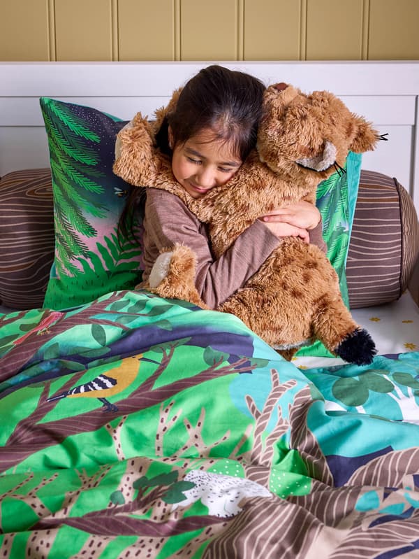 Dievčatko v posteli s obliečkami SKOGSDUVA drží v náručí rysa SKOGSDUVA.