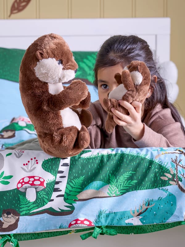 Dievčatko v posteli s obliečkami SKOGSDUVA sa hrá s plyšovou vydrou s mláďatkom  SKOGSDUVA.