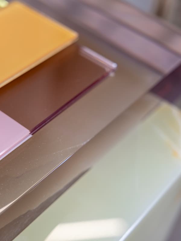 Different sheets of coloured glass are stacked on top of each other.