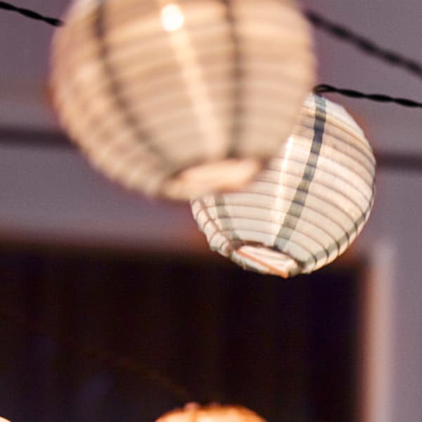Different types of lighting chains hanging on a balcony outside a window at night. The lighting chains are lit.
