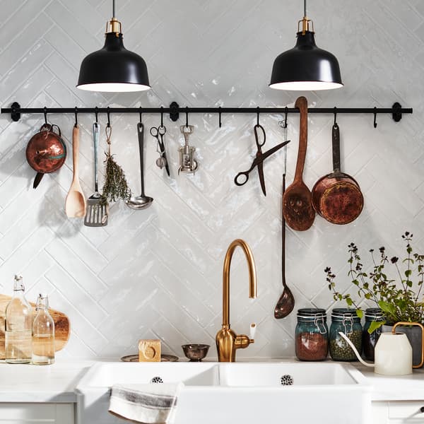 Dinding berjubin putih dengan rel lekapan dinding FINTORP yang bercangkuk. Herba, perkakas dapur dan barang hiasan digantung di sini.