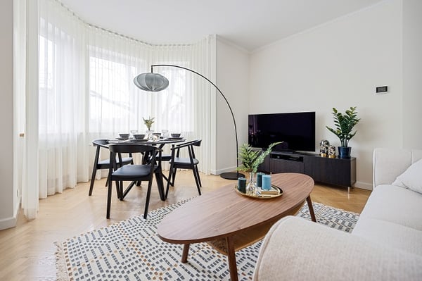 Dining area with black chairs, round table, and modern floor lamp near TV