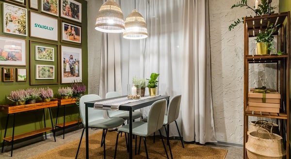 Dining space with light green chairs, wall art, and plants on wooden console tables
