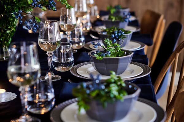 Dining table set with elegant drinkware, plates and bowls with green salad.