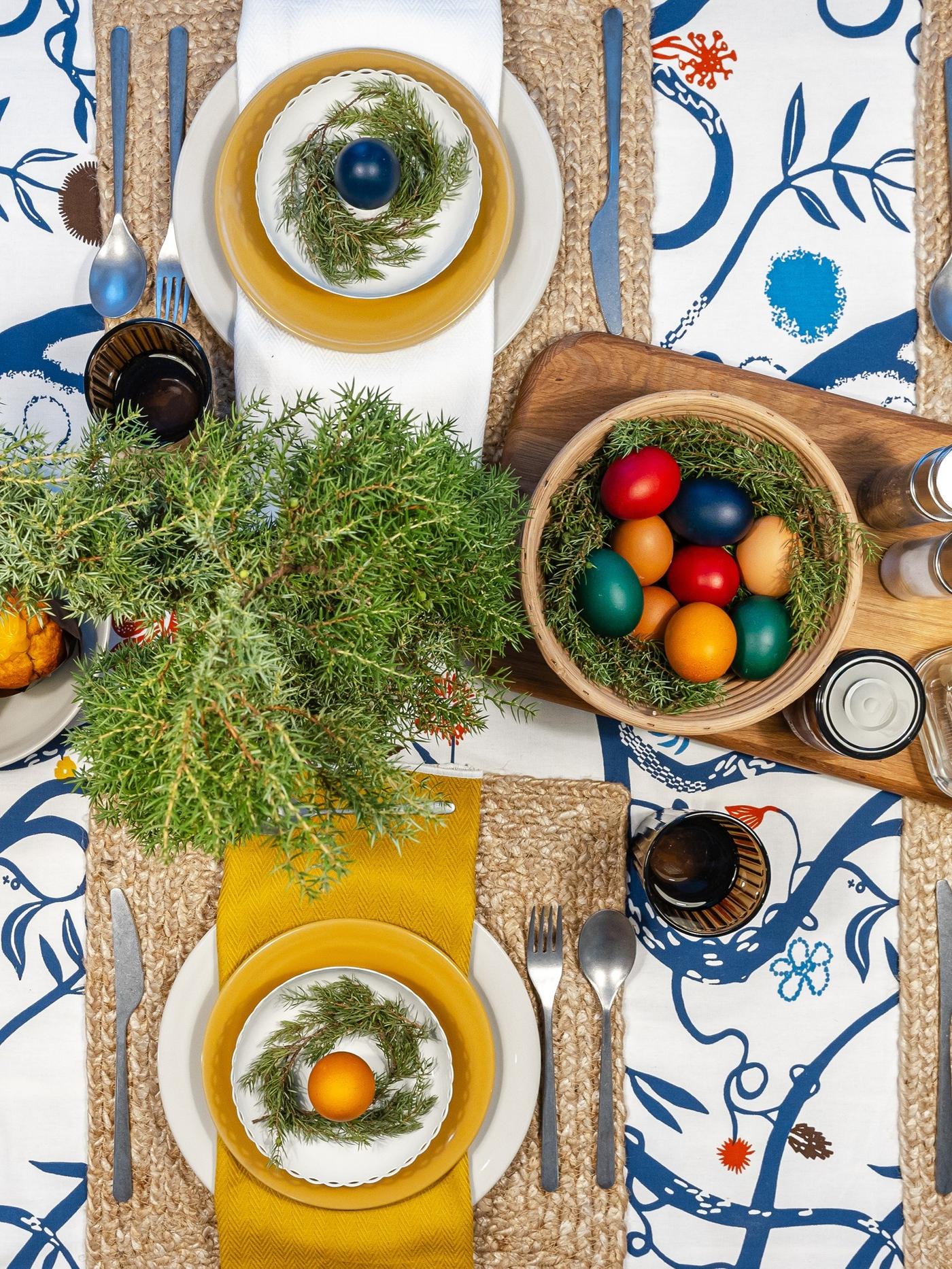 Dining table styled with a bold floral tablecloth, greenery and mixed tableware for a relaxed, cosy feel.