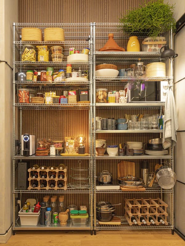 Dispensa della cucina formata da due scaffali a vista contenenti contenitori, bottiglie e oggetti utili per cucinare.