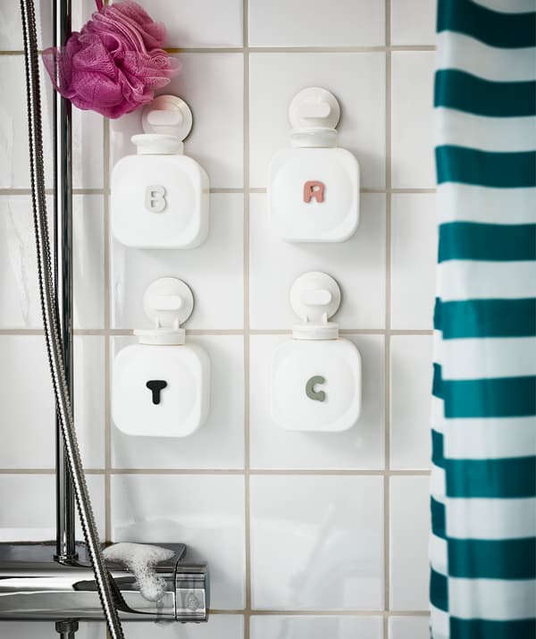 Dispenser per sapone personalizzati per ogni membro della famiglia appesi sulle piastrelle di una doccia.