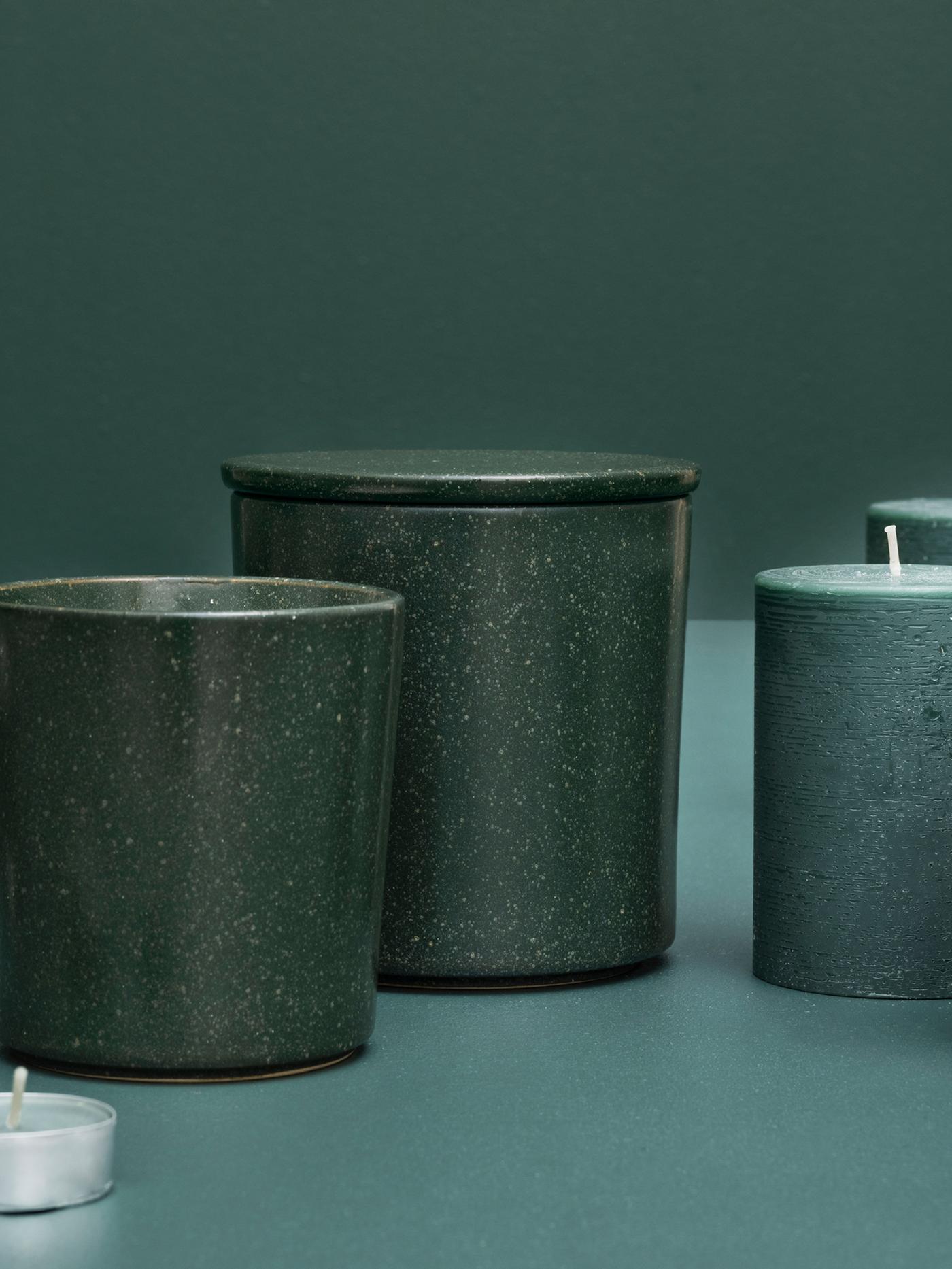 Disposizione artistica di candele AVMÅLA al profumo di menta in diversi contenitori su uno sfondo verde scuro - IKEA.