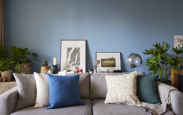 Divano grigio con cuscini sullo sfondo di una parete blu - IKEA