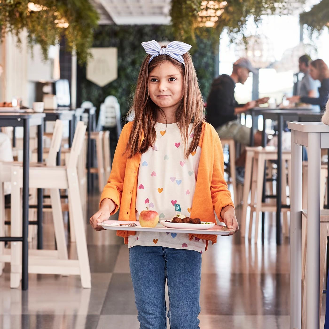 Dívka nesoucí si tác dětský menu