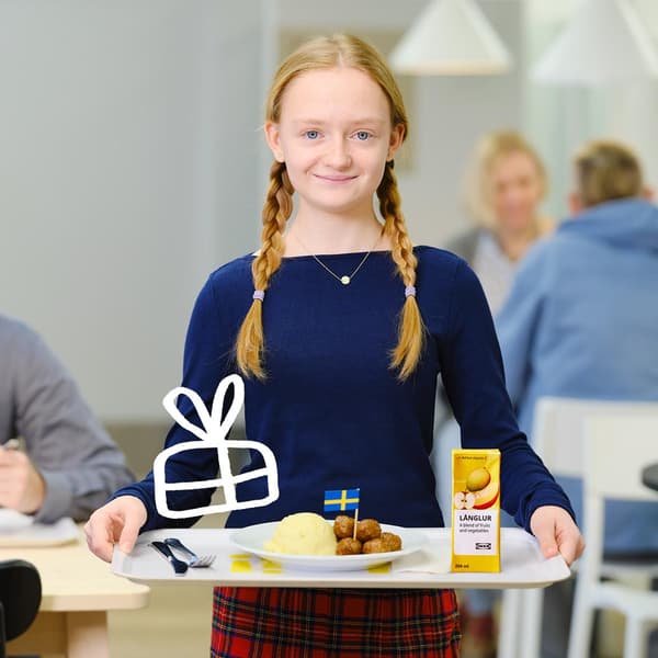 Dívka stojící s talířem plným bramborové kaše a masových kuliček z Ikei