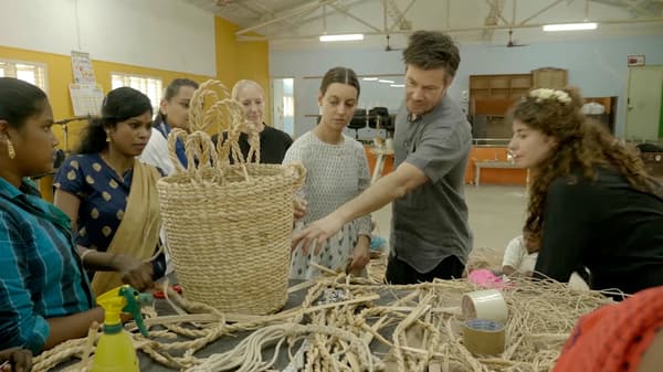 Дизайнери IKEA та жінки-майстрині з Індії обговорюють техніки плетіння у приміщення фабрики.