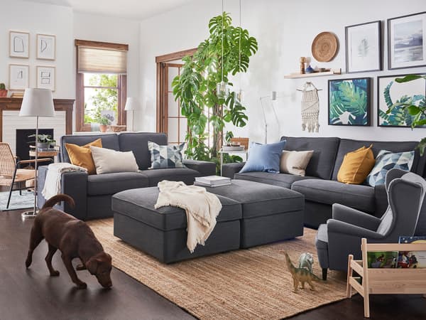 ダークグレーの大型ソファを置いた広々リビング。観葉植物と木製家具でナチュラルな空間。