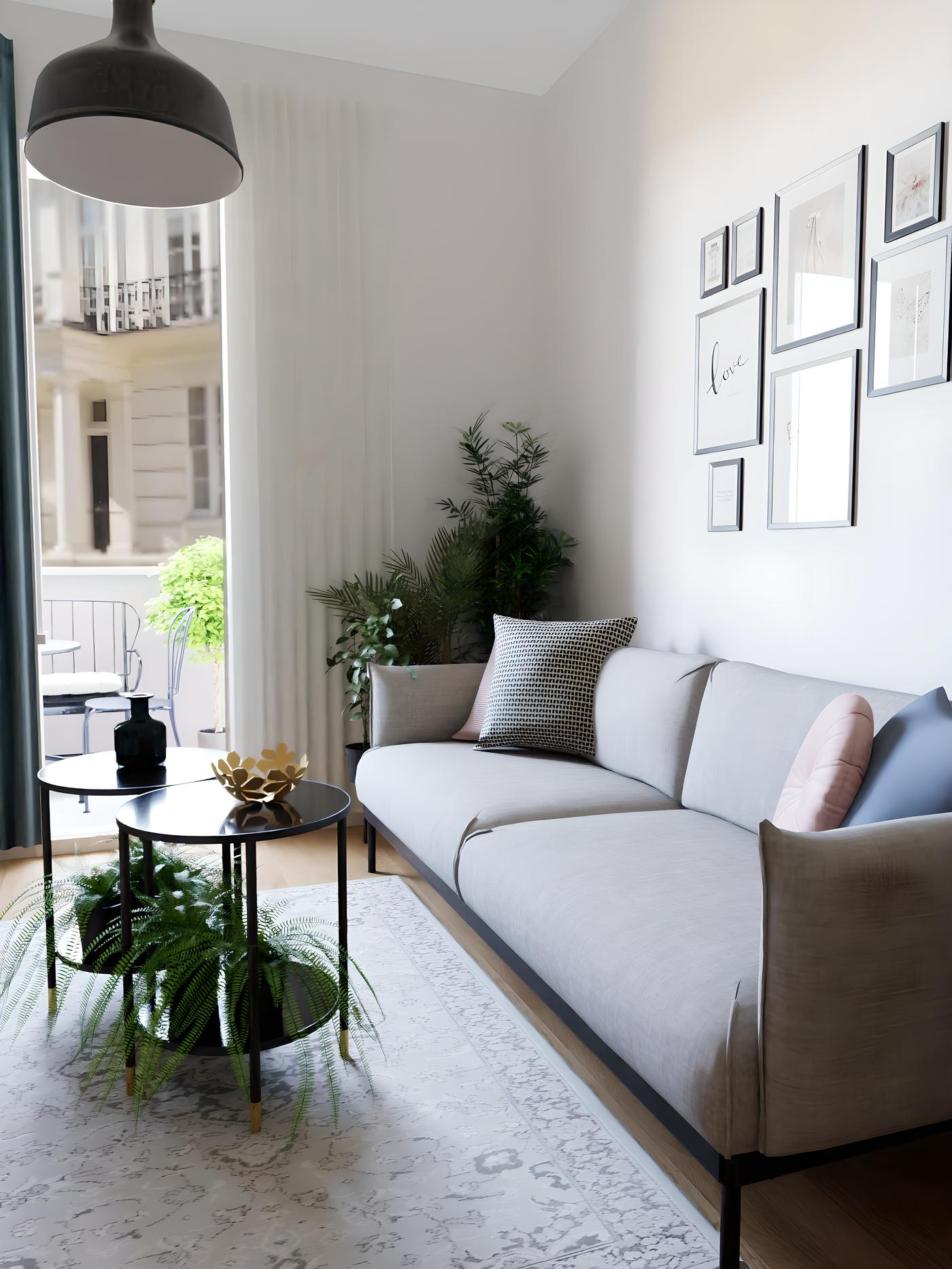 Dnevni boravak s modernim sivim kaučem, okruglim stolićem, biljkama i zidnim slikama.