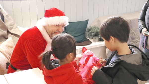 子どもたちにサンタクロースがプレゼントを配っている