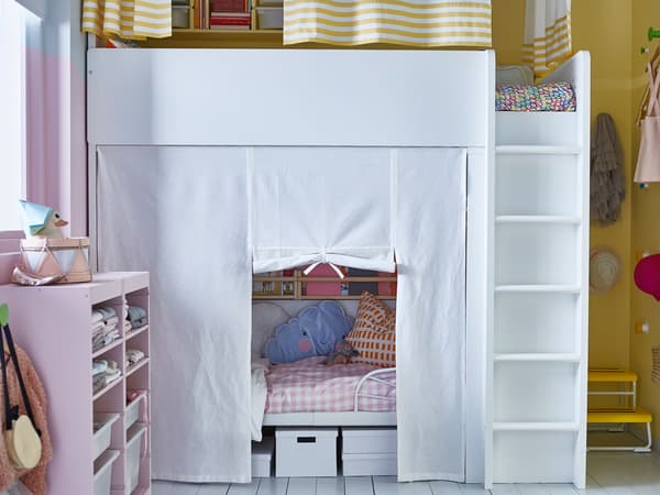 Dormitori infantil compartit amb dos llits, un d'alt i un altre a sota amb cortina.