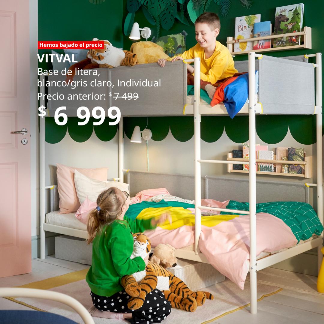 Dormitorio infantil colorido con base de litera VITVAL, cama superior con niño y peluches, cama inferior junto a otro niño, paredes verdes con diseño de hojas, puerta rosa y ropa de cama en tonos pastel; diseño seguro, funcional y divertido.
