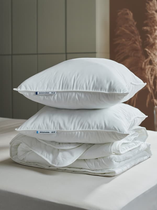 Dos almohadas SKOGSFRÄKEN blancas apiladas una sobre la ora sobre ropa de cama IKEA 