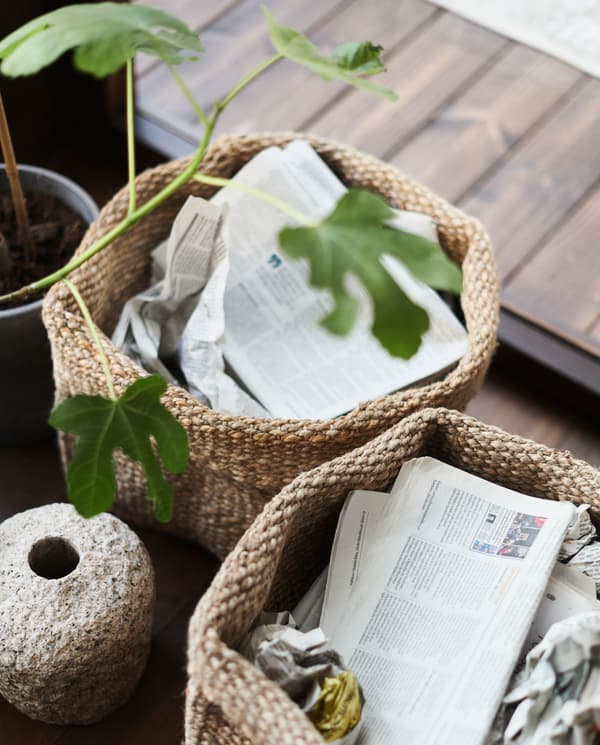Dos canastos de yute con diarios y plantas en su interior.