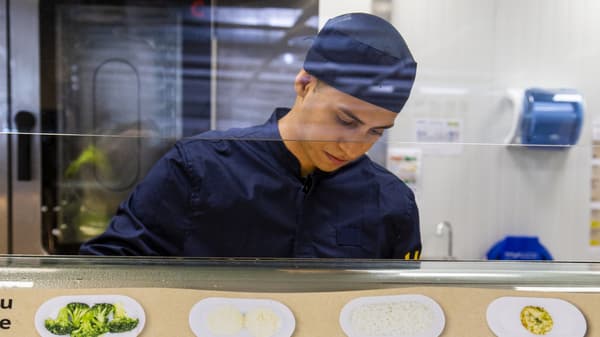 Dos col·laboradors d'IKEA amb uniformes de color blau fosc fan bromes mentre prenen un tast.