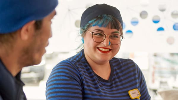 Dos col·laboradors/es d'IKEA, una amb els cabells blaus, amb un got d'aigua a la cantina.