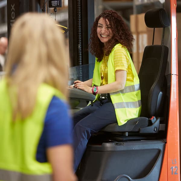 Dos colaboradoras de IKEA, vestidas con uniformes del personal de IKEA, disfrutan de un café juntas en la cantina.