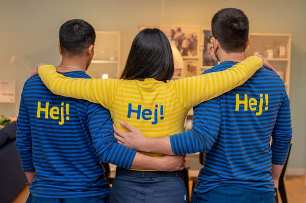 Dos colaboradoras y un colaborador hombre vestidos con poleras amarillas y azules de IKEA sonriendo.