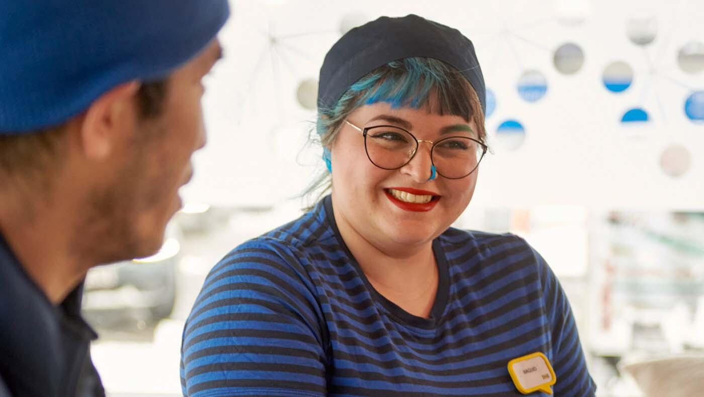Dos colaboradores/as de IKEA, una con el pelo azul, con un vaso de agua en la cantina.