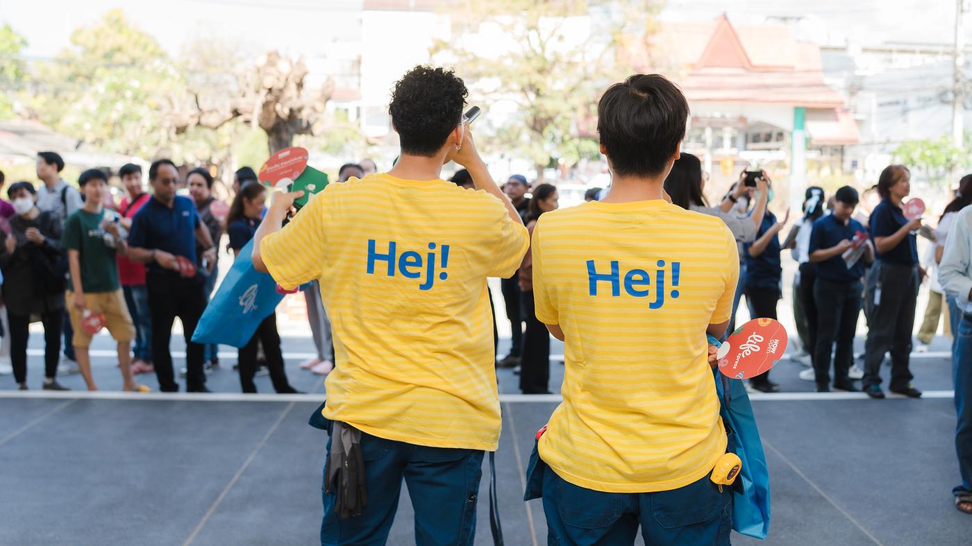 Dos colaboradores de IKEA con uniformes amarillos de cara a una multitud en el punto de pedidos de IKEA Chiang Mai, Tailandia