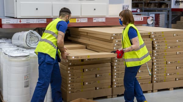 Dos colaboradores de IKEA en el autoservicio colocando unos paquetes planos.