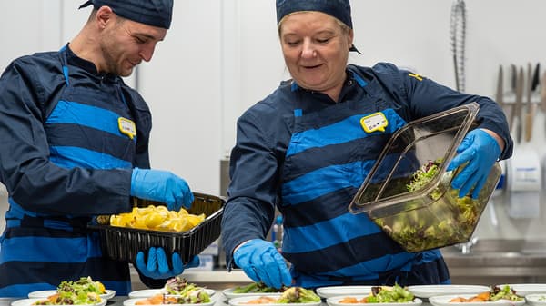 Dos colaboradores de IKEA Food colocando comida en unos platos.