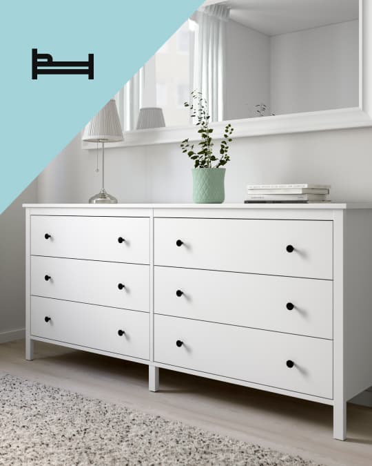 Dos comodas IKEA blancas de 3 cajones y en el costado superior izquierdo de la foto un ícono de cama.