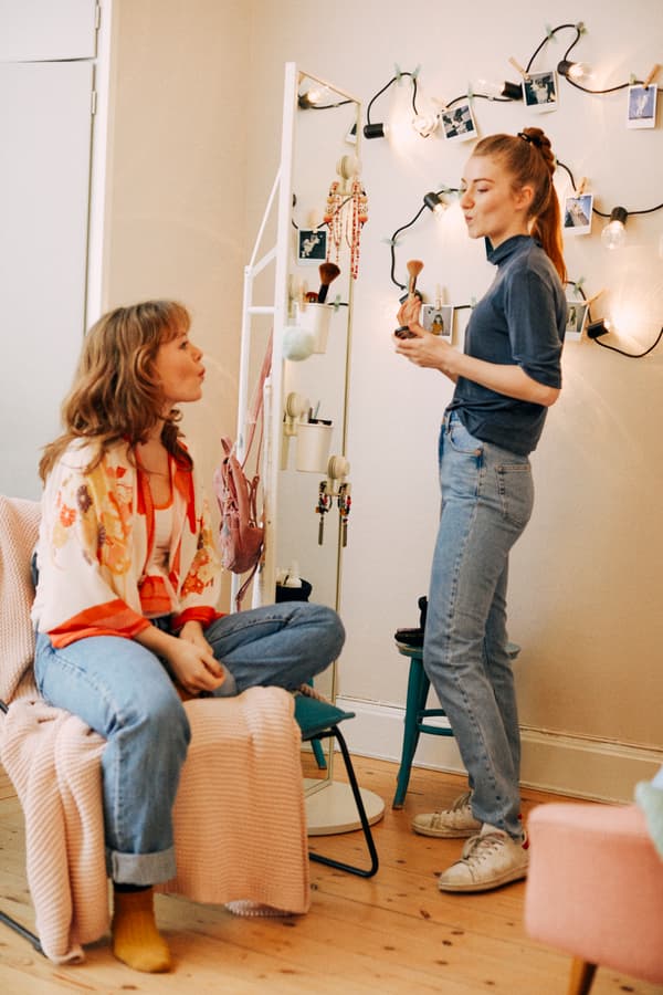 dos jovenes hablando entre ellas en un dormitorio.