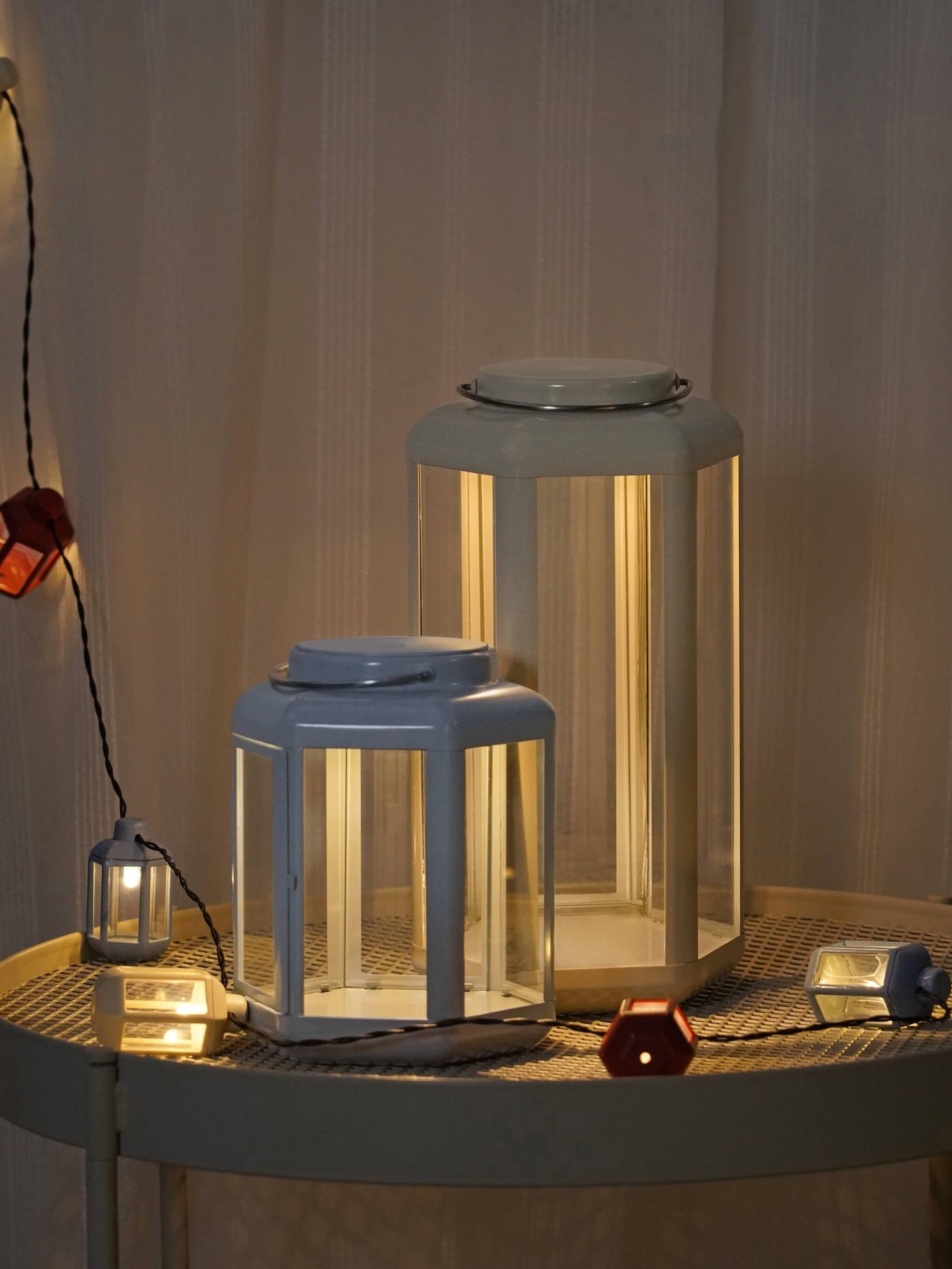 Dos linternas azules de exterior con guirnaldas de luces colgadas sobre la mesa.