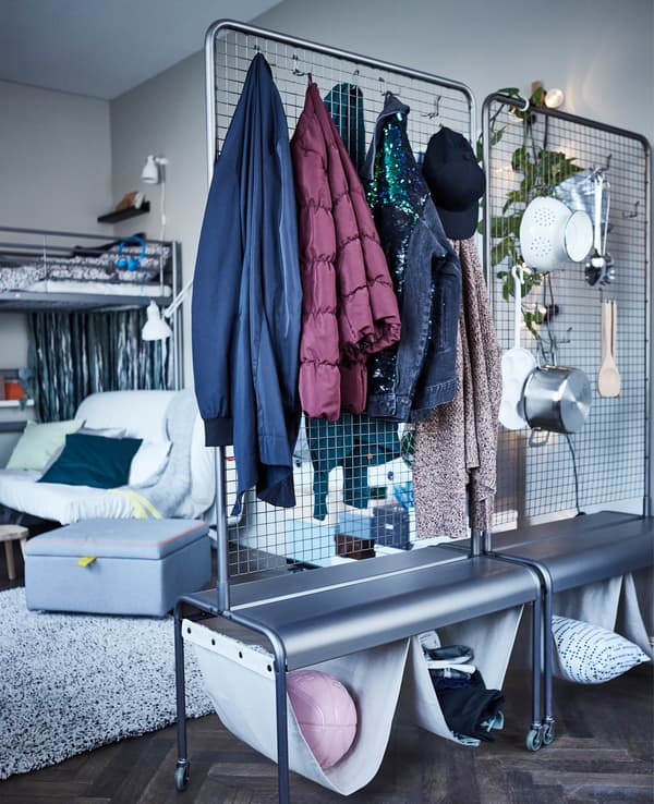 Dos paravents IKEA VEBERÖD utilitzats d’emmagatzematge sobre rodes amb roba penjada i estris de cuina.