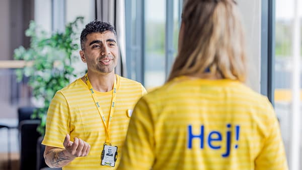 Dos personas con camisetas amarillas de IKEA entablan una conversación