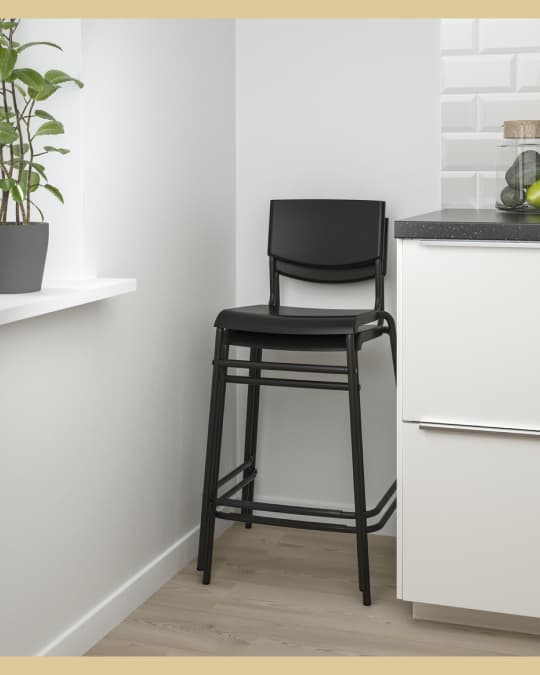 Dos sillas altas para barra una sobre la otra al costado de un mueble de cocina.